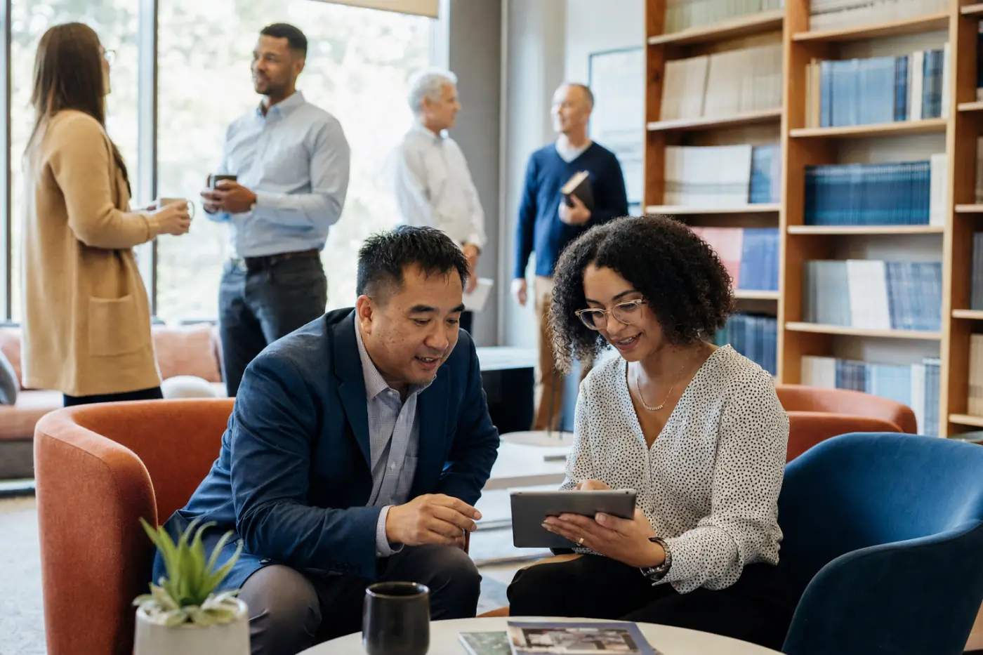 Association members talking over a tablet in a library lounge