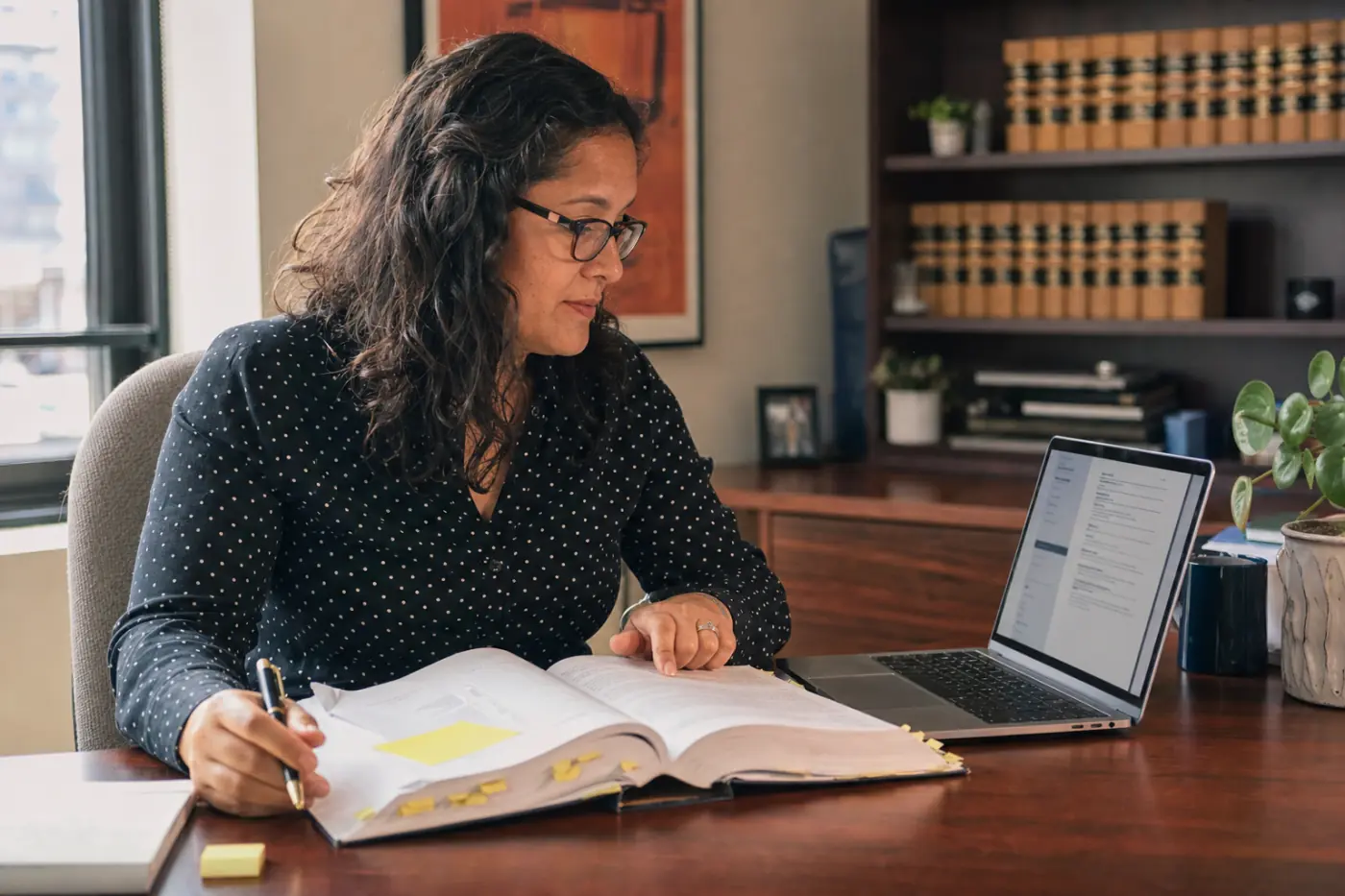 A publications manager comparing a printed legal practice manual with its digital ebook edition on a laptop